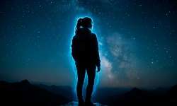 Técnica de relajación de la Luz Azul Mujer con un aura azul en lo alto de una montaña por la noche y con cielo estrellado