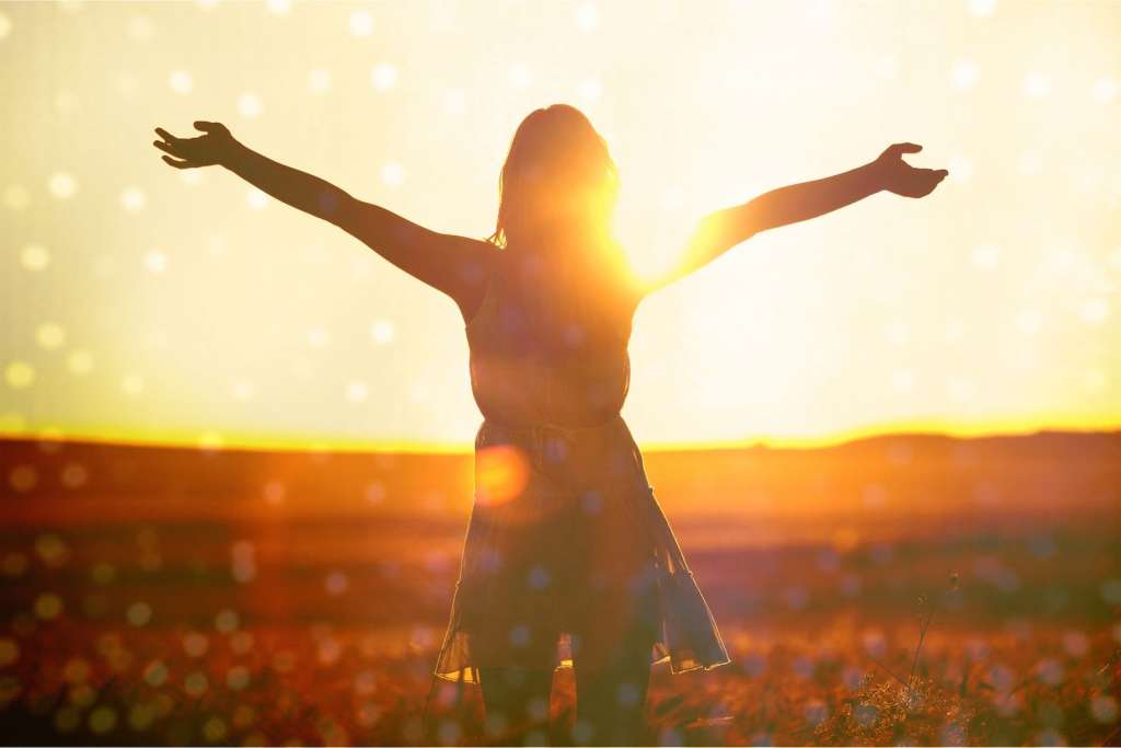 Mujer saludando al sol y recuperando la energía positiva y quitando energía negativa.