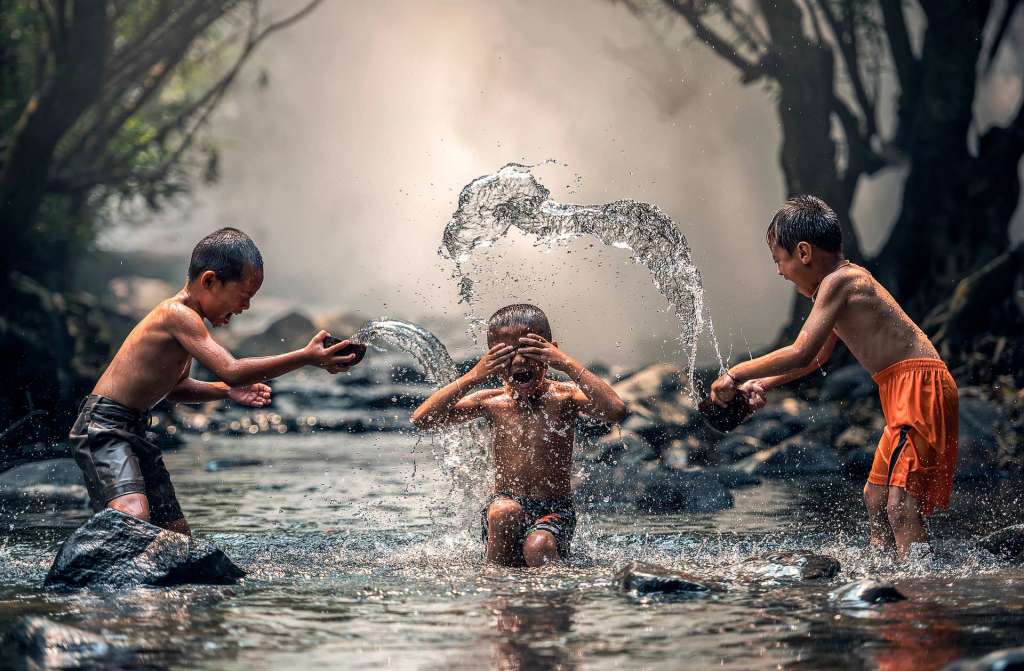 Tres niños jugando en un rio y el concepto de volver a ser felices