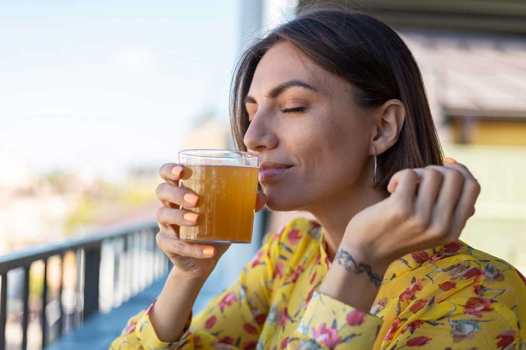 Mujer disfrutando de una taza de te con los ojos cerrados y la alimentación consciente