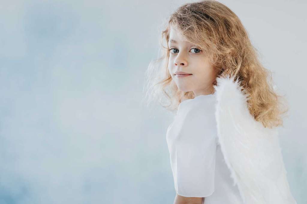 Una niña vestida de blanco y con alas de angel.