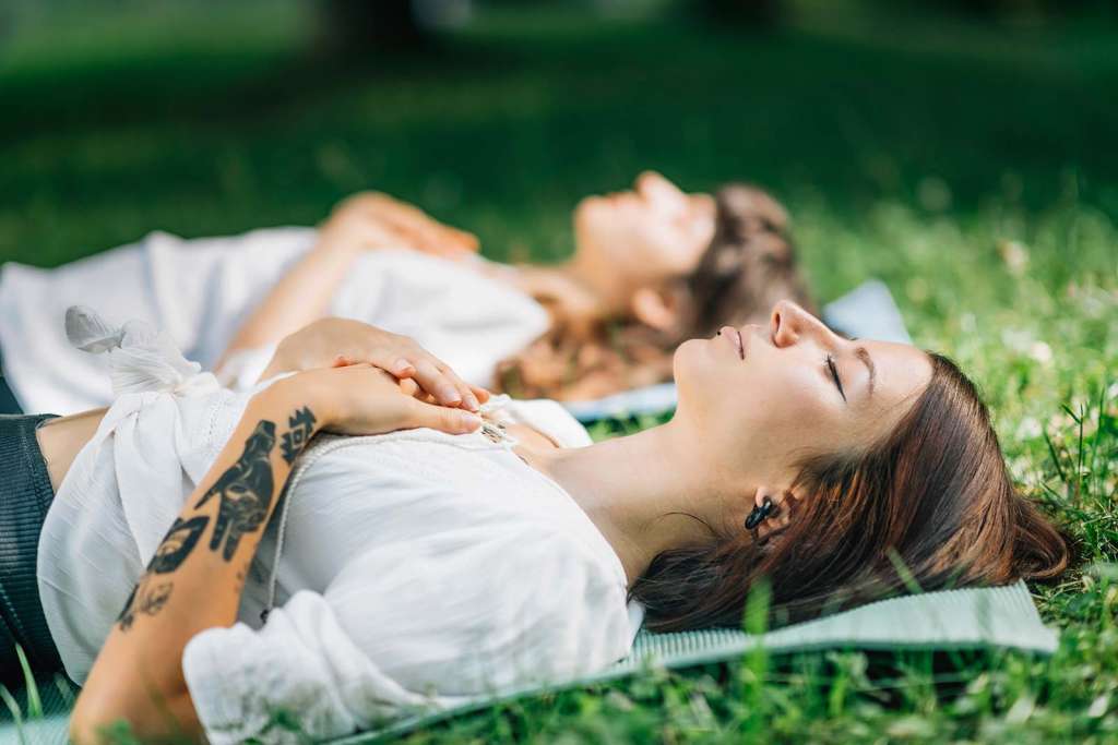 Dos chicas tumbadas en la hierba meditando